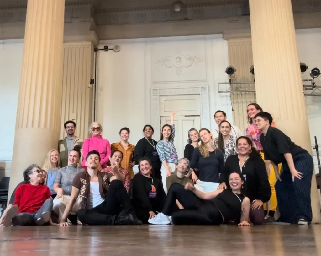 Cinthia Durán with a group of workshop participants in a columned ballroom