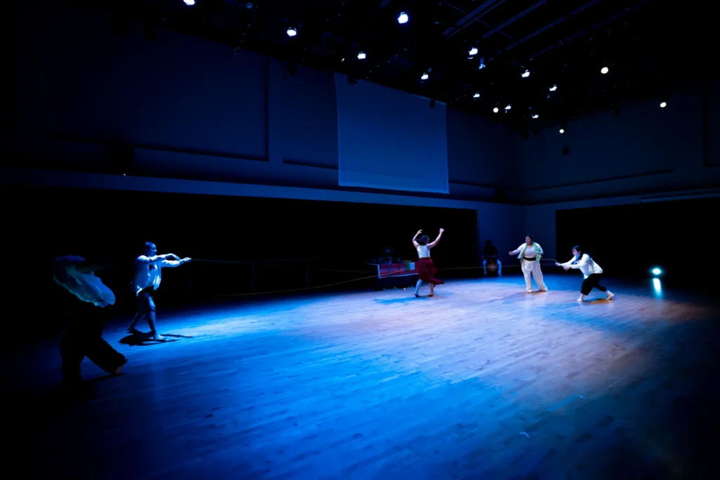 Ritwal — a full-stage image in blue light, the cast connected by a length of cord, UC Riverside Department of Dance, Spring Forward 2023